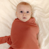 Baby wearing ballu baby bamboo onesie and bamboo swaddle blanket in watermelon color