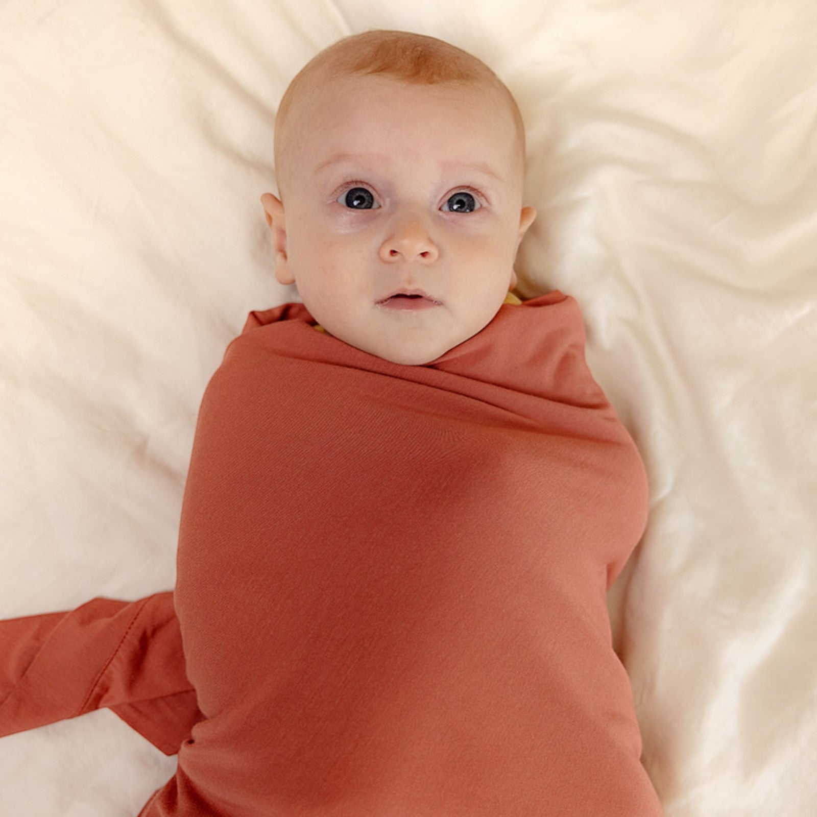 Baby wearing ballu baby bamboo onesie and bamboo swaddle blanket in watermelon color