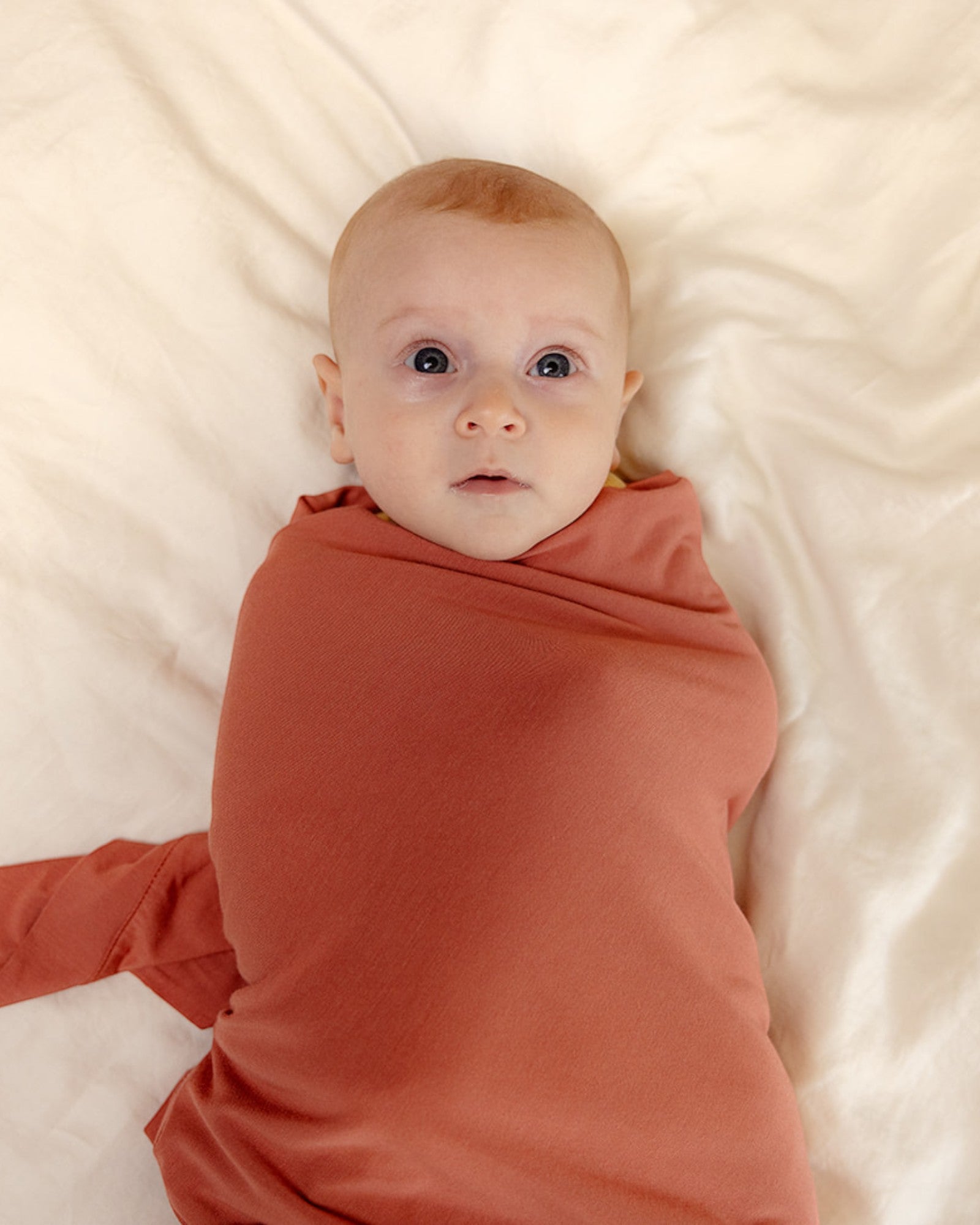 Baby wearing ballu baby bamboo onesie and bamboo swaddle blanket in watermelon color