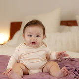 Baby wearing bamboo & organic cotton bodysuit and onesie in light almond beige color