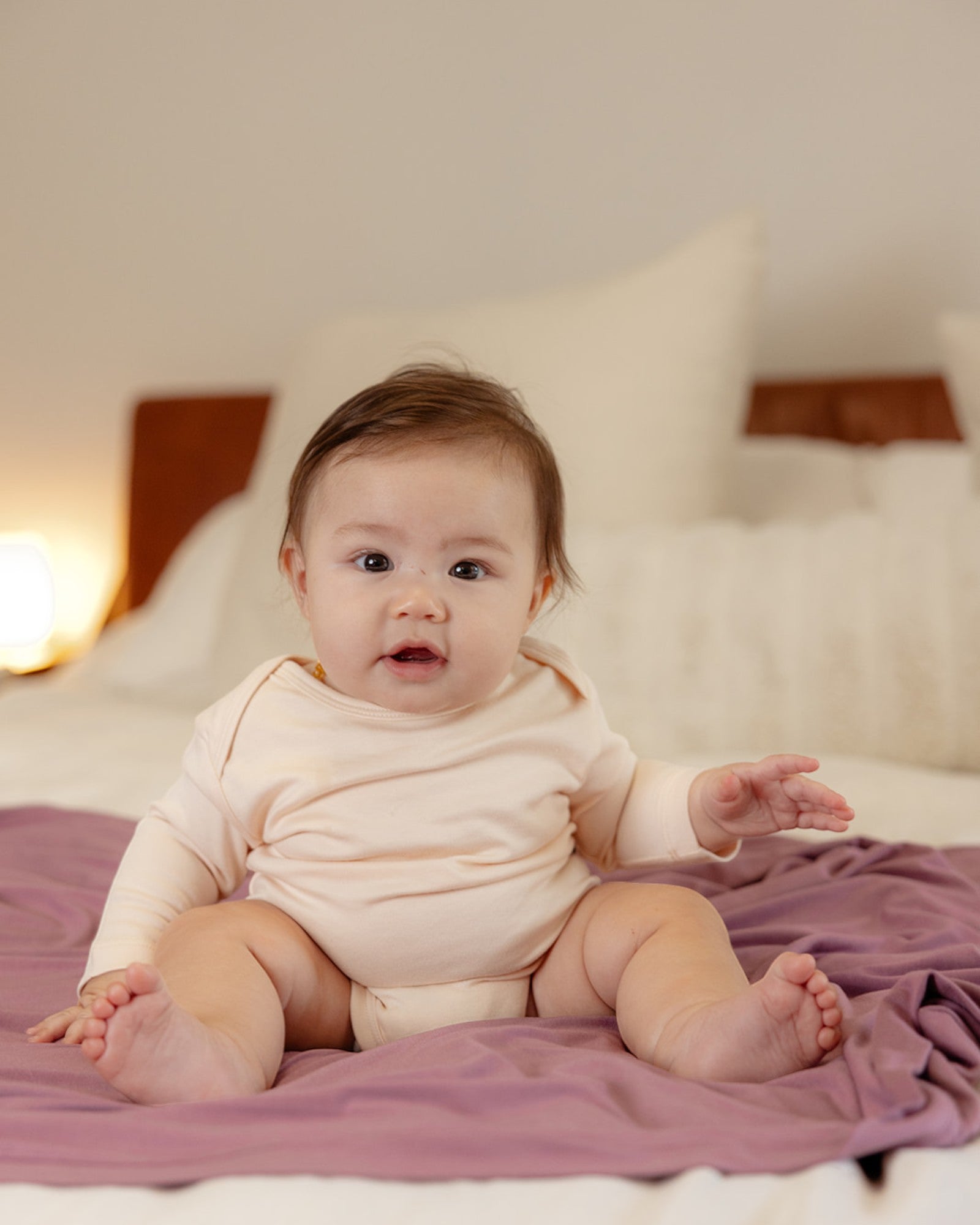 Baby wearing bamboo & organic cotton bodysuit and onesie in light almond beige color