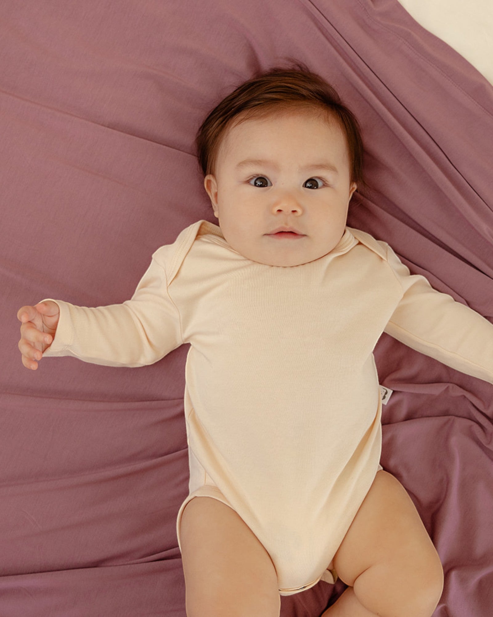 Baby wearing ballu baby bamboo onesie and bamboo swaddle blanket in lavender color