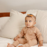 Baby wearing ribbed bamboo zipper romper in sand beige color