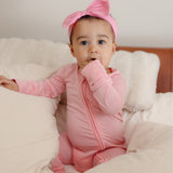 Baby wearing bamboo zip romper/sleeper in peony pink color
