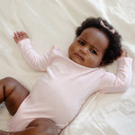 Baby wearing bamboo & organic cotton bodysuit and onesie in sakura pink color 
